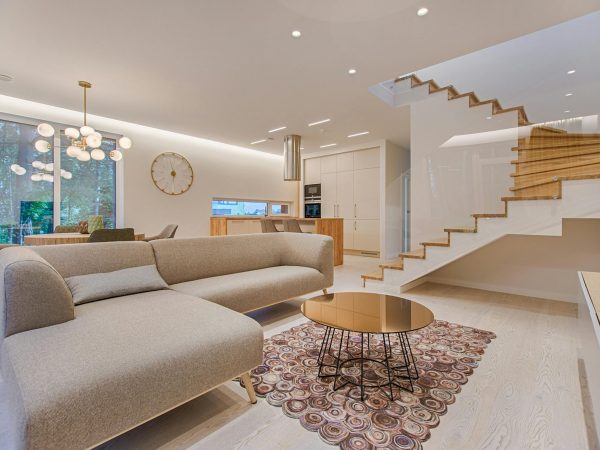 Contemporary living room with neutral tones, a sleek sofa, and elegant wooden staircase.