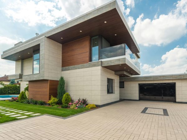 Contemporary luxury house with a sleek design, lush garden, and blue sky.